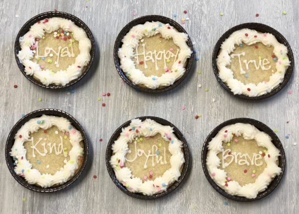6 round sugar cookies with words Loyal, Happy, True, Kind, Joyful, and Brave